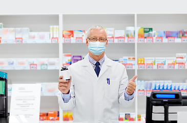 Image showing senior apothecary in mask with drug at pharmacy