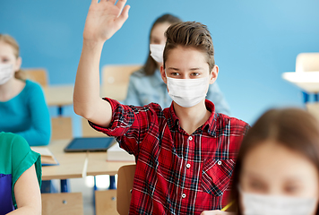 Image showing student boy in mask with raised hand at school