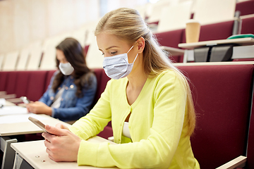 Image showing student girls in masks with smartphones on lecture