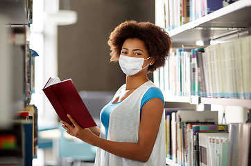 Image showing african student girl in mask with book at library