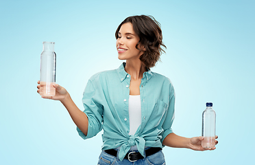 Image showing smiling young woman comparing bottles of water