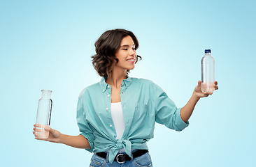 Image showing smiling young woman comparing bottles of water