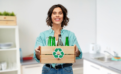 Image showing smiling young woman sorting glass waste at home