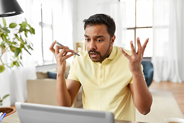 Image showing man with laptop recording voice on phone at home