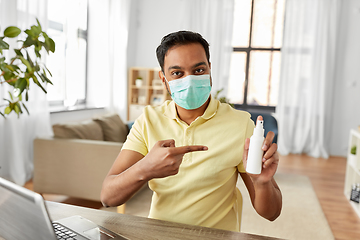 Image showing man in mask showing hand sanitizer at home office