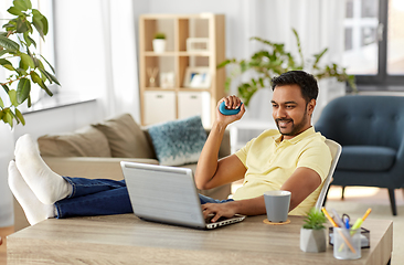 Image showing man with laptop and hand expander at home office