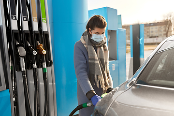 Image showing woman in mask filling car at gas station