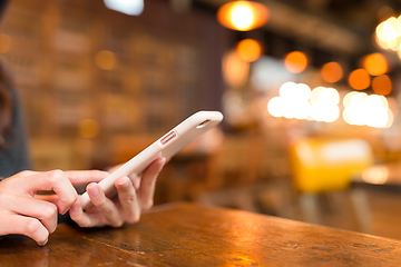 Image showing Woman sending sms on cellphone in coffee shop