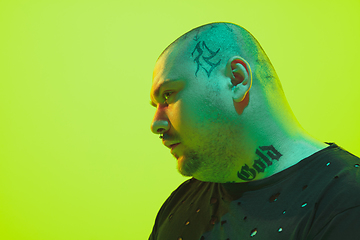 Image showing Portrait of a guy with colorful neon light on green background