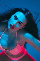 Image showing Attractive brunette model on blue studio background in neon light