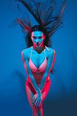 Image showing Attractive brunette model on blue studio background in neon light