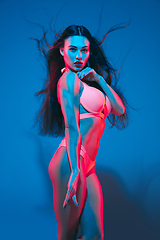 Image showing Attractive brunette model on blue studio background in neon light