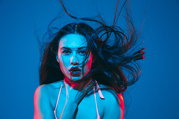 Image showing Attractive brunette model on blue studio background in neon light