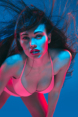 Image showing Attractive brunette model on blue studio background in neon light