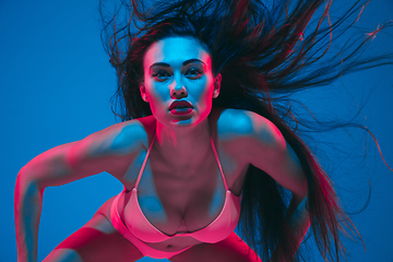 Image showing Attractive brunette model on blue studio background in neon light