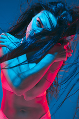 Image showing Attractive brunette model on blue studio background in neon light