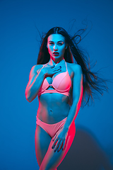 Image showing Attractive brunette model on blue studio background in neon light