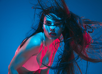 Image showing Attractive brunette model on blue studio background in neon light