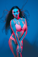 Image showing Attractive brunette model on blue studio background in neon light