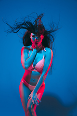 Image showing Attractive brunette model on blue studio background in neon light