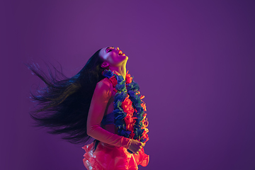 Image showing Attractive hawaiian brunette model on purple studio background in neon light