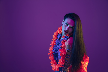 Image showing Attractive hawaiian brunette model on purple studio background in neon light