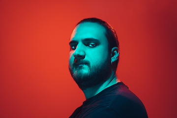 Image showing Portrait of a guy with colorful neon light on red background - cyberpunk concept