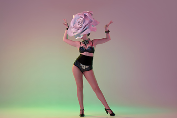 Image showing Young female dancer with huge floral hats in neon light on gradient background