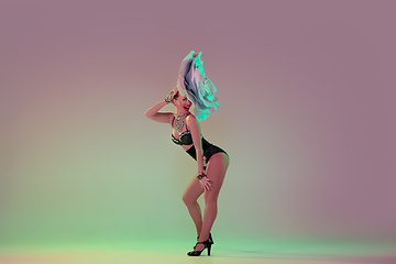 Image showing Young female dancer with huge floral hats in neon light on gradient background