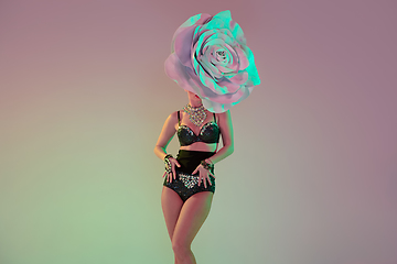 Image showing Young female dancer with huge floral hats in neon light on gradient background