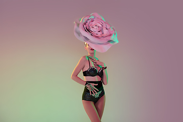 Image showing Young female dancer with huge floral hats in neon light on gradient background