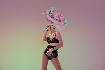 Image showing Young female dancer with huge floral hats in neon light on gradient background