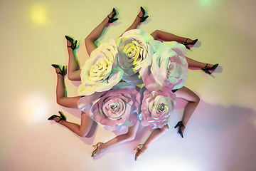 Image showing Young female dancers with huge floral hats in neon light on gradient background