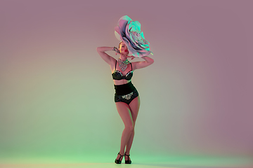 Image showing Young female dancer with huge floral hats in neon light on gradient background