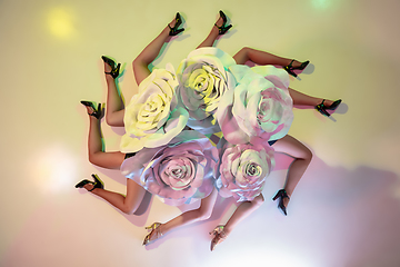 Image showing Young female dancers with huge floral hats in neon light on gradient background
