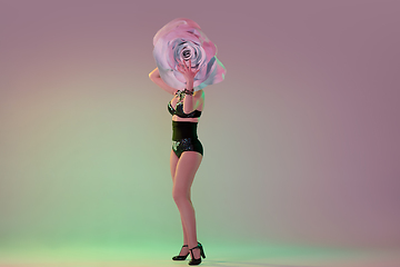 Image showing Young female dancer with huge floral hats in neon light on gradient background