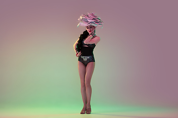 Image showing Young female dancer with huge floral hats in neon light on gradient background