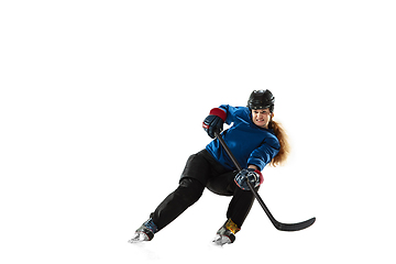 Image showing Young female hockey player with the stick on ice court and white background