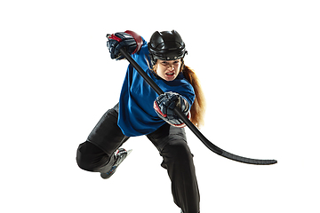 Image showing Young female hockey player with the stick on ice court and white background