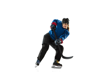 Image showing Young female hockey player with the stick on ice court and white background