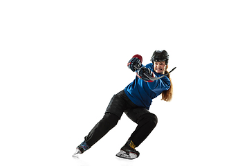 Image showing Young female hockey player with the stick on ice court and white background