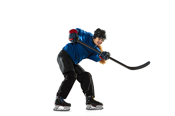 Image showing Young female hockey player with the stick on ice court and white background