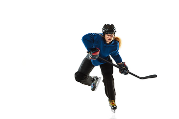 Image showing Young female hockey player with the stick on ice court and white background