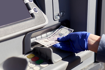 Image showing hand in medical glove with money at atm machine