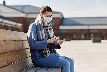 Image showing woman in mask spraying hand sanitizer outdoors