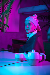 Image showing Beautiful girl with a pearl earring taking lunch in modern cafe, restaurant in neon light