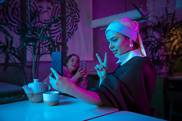 Image showing Beautiful girl with a pearl earring taking lunch in modern cafe, restaurant in neon light