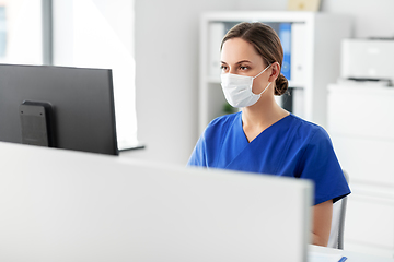 Image showing doctor or nurse in mask with computer at hospital