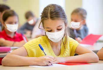 Image showing group of students in masks writing test at school