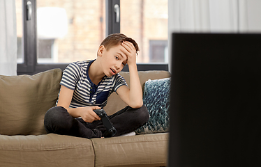 Image showing sad boy with gamepad playing video game at home